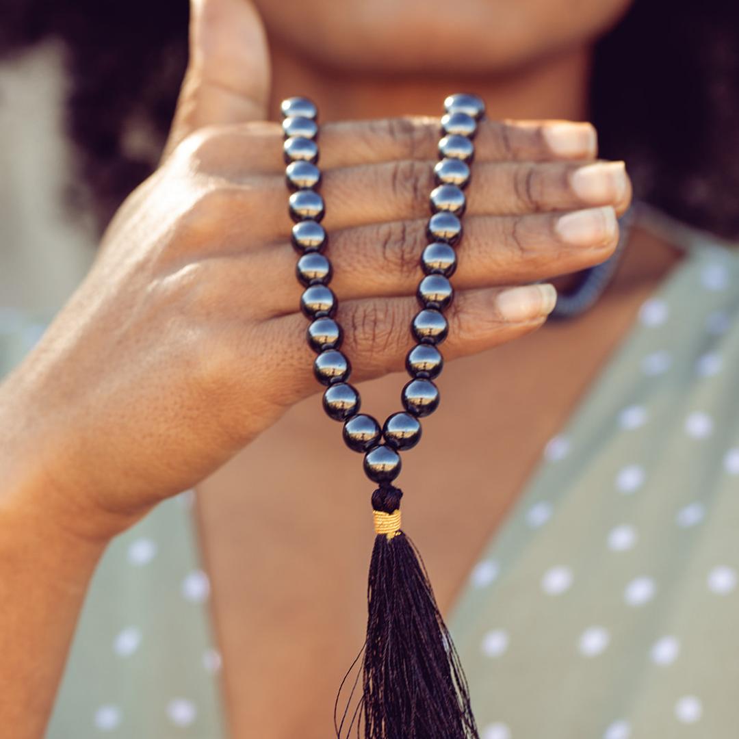 Ambarya Strength - Hematite Mala Bead Necklace draped across woman's hand