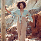 Woman standing at the beach. There are rocks behind her. She is wearing Ambarya New Beginnings - Moonstone Mala Bead set