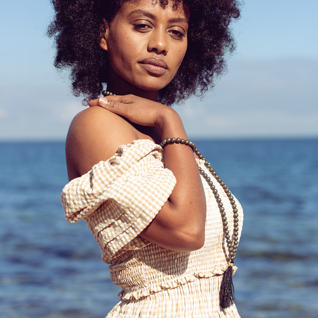 Close up of woman standing at the beach wearing Ambarya Willpower - Pyrite Mala Bead Set