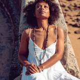 Woman lying back against a stone wall, looking up and wearing Ambarya Good health - Bloodstone Mala Bead Set