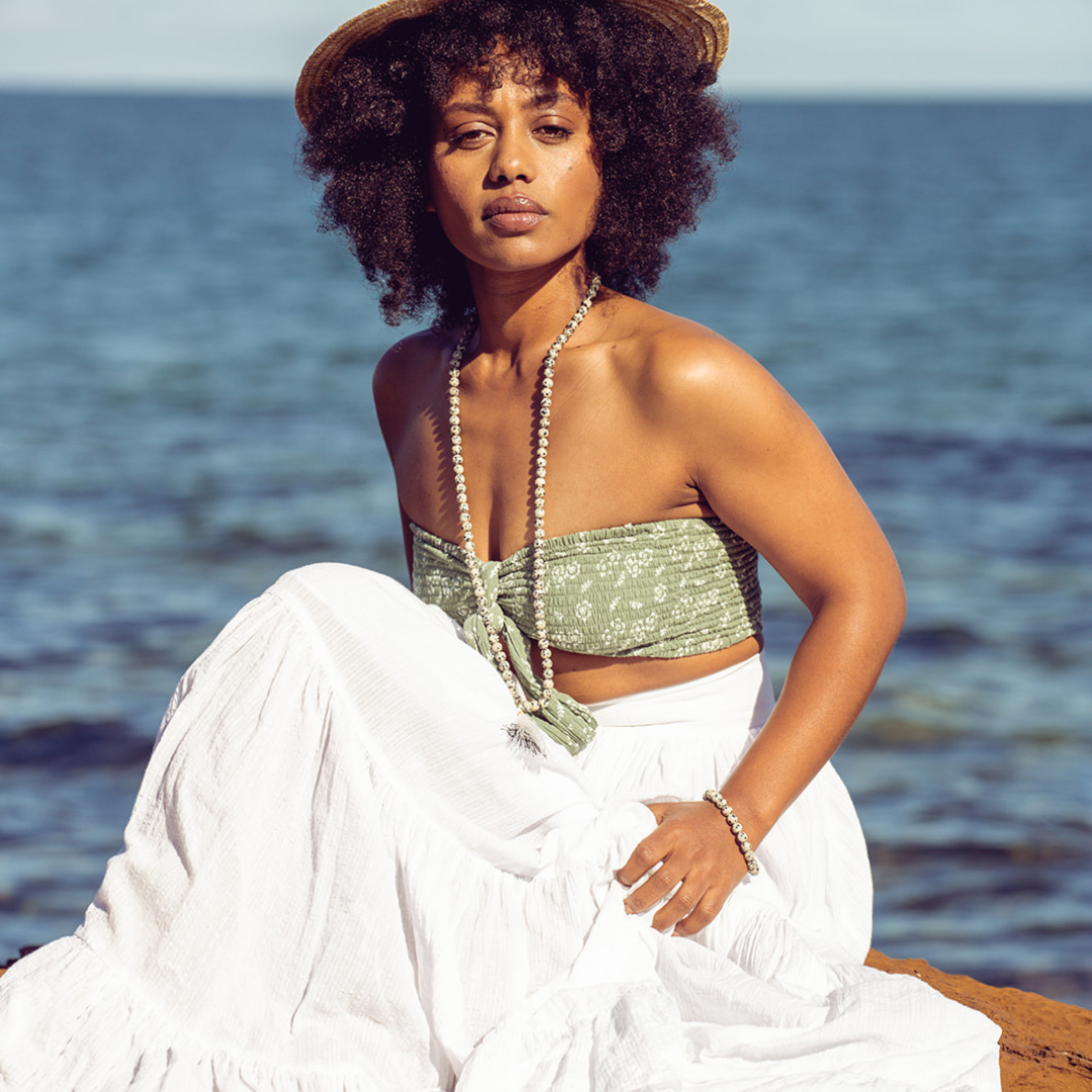 Woman sitting in the sun with water in the background she is wearing Ambarya Playfulness - Dalmation Stone Mala Bead Set