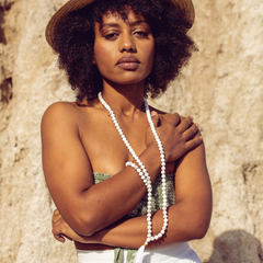 Woman looking at the camera, with rocks in the background, wearing Ambarya Patience - Howlite Mala Bead Set