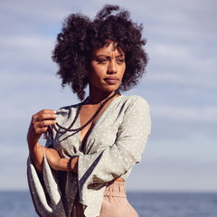 Woman standing outside, looking out wearing Ambarya Release - Smoky Quartz Mala Bead Set