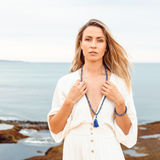 Woman with fair skin, blonde hair and a white dress, looking at the camera wearing Ambarya Wisdom - Lapis Lazuli Mala Bead Set