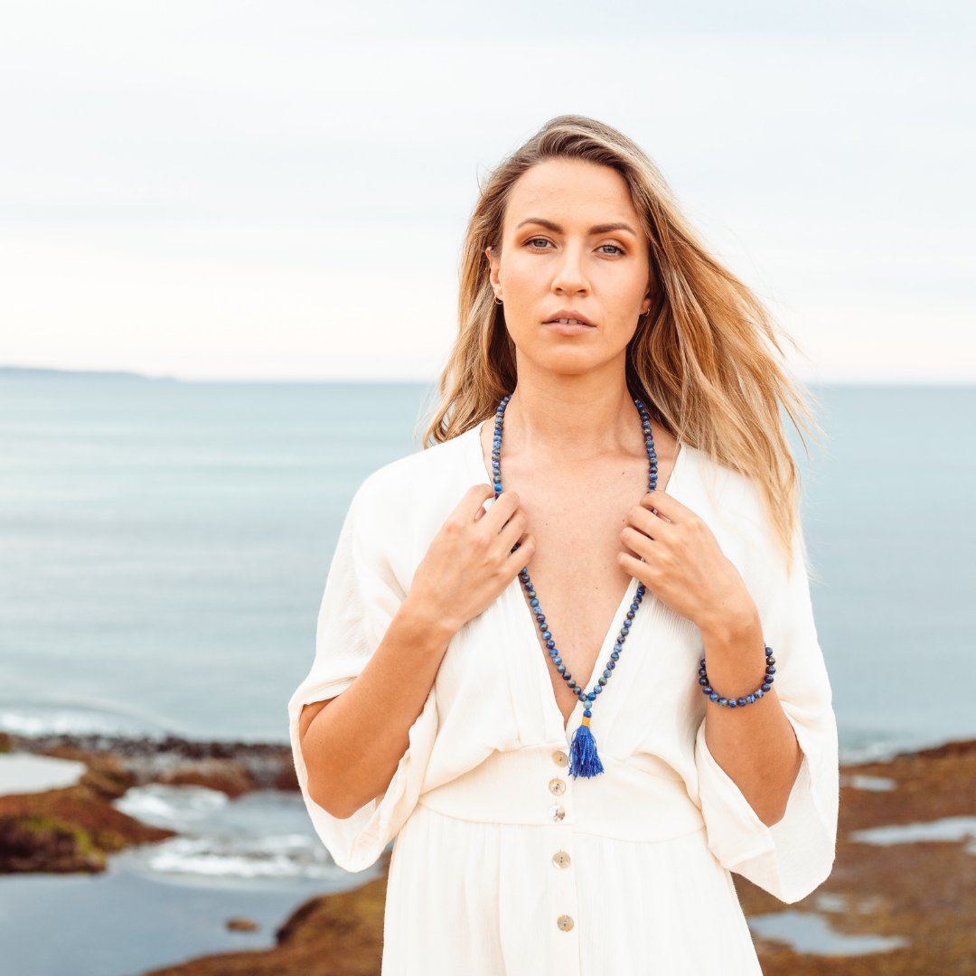 Woman with fair skin, blonde hair and a white dress, looking at the camera wearing Ambarya Wisdom - Lapis Lazuli Mala Bead Set